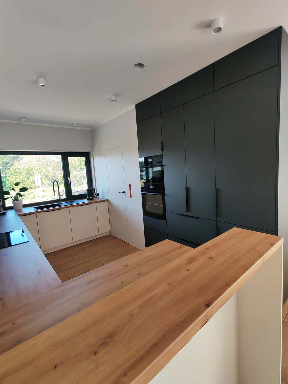 Nowoczesna kuchnia z białymi frontami i drewnianym blatem - realizacja wykonana przez Mondins Meble